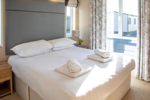 a large white bed with towels on top of it at Nature Haven Hot Tub Lodge 30 Cameron, St Andrews in St. Andrews