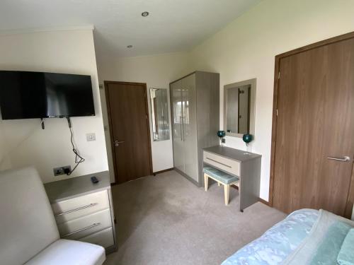 um quarto com uma cama, uma secretária e uma televisão em Lakeview Lodge em Wisbech