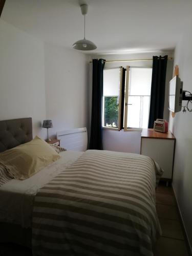 - une chambre avec un lit avec une couverture rayée et 2 fenêtres dans l'établissement Les Glycines de Saint Bo, à Saint-Bonnet-en-Champsaur