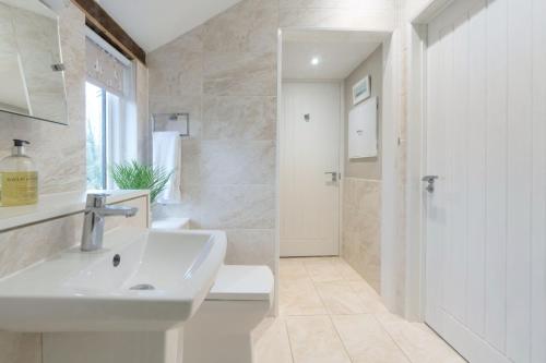 a white bathroom with a sink and a shower at The Granary, Cretingham in Woodbridge