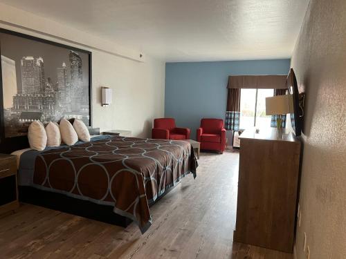 a hotel room with a bed and a red chair at Super 8 by Wyndham Clemmons - Bermuda Run - Winston-Salem I-40 in Clemmons