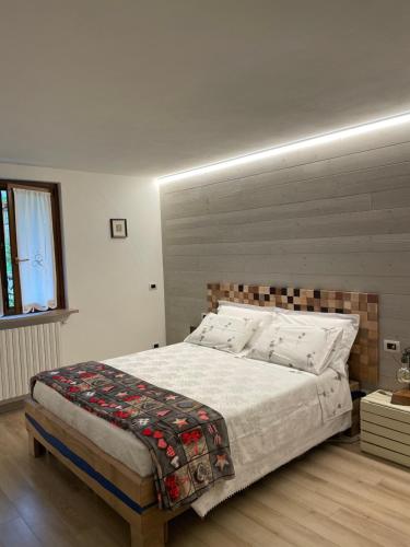 een slaapkamer met een groot bed met een houten hoofdeinde bij B&B Carmen in San Giovanni Bianco