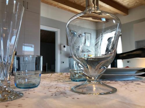 a clear glass vase sitting on a table with glasses at Appartamento incantevole con parcheggio privato in Casteldidone