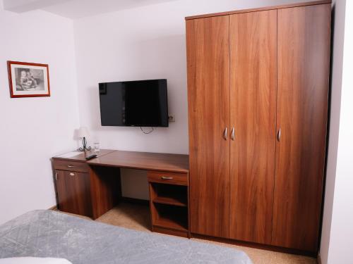 a bedroom with a desk with a tv and a wooden cabinet at Stara Ada Banja Luka in Banja Luka