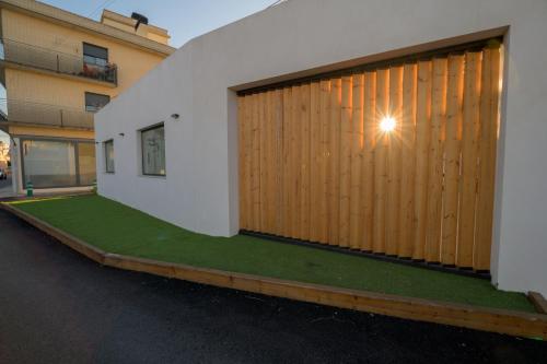 a building with a wooden garage door with a green lawn at Casa Casver in Deltebre