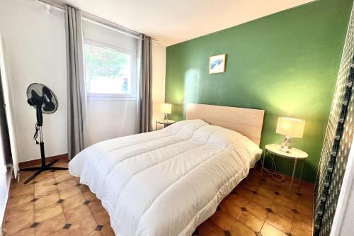 une chambre avec un lit blanc et un mur vert dans l'établissement Old-world charm with modern comforts, à Fréjus