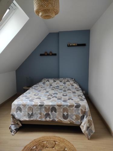 a bedroom with a bed and a blue wall at La Petite Chaume in Châteauroux