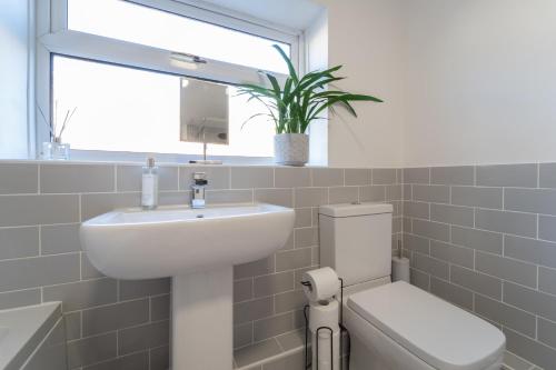 a bathroom with a sink and a toilet and a window at Southview Stays - Three bedroom House in Chester