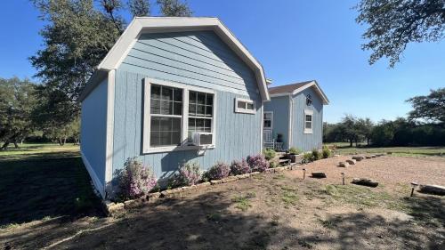 een klein blauw huis met een raam in een tuin bij Hill Country Highland's Bluebonnet Cottage in Marble Falls