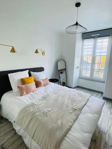 une chambre avec un grand lit blanc avec des oreillers dans l'établissement Appartement de charme 1er etage, à Saint-Samson-sur-Rance