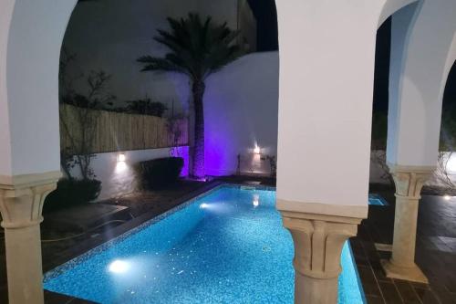 una piscina en una casa por la noche con luces moradas en Villa des Lotophages, en Djerba
