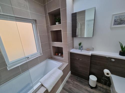 een badkamer met een bad, een wastafel en een raam bij Hill View in Abertillery