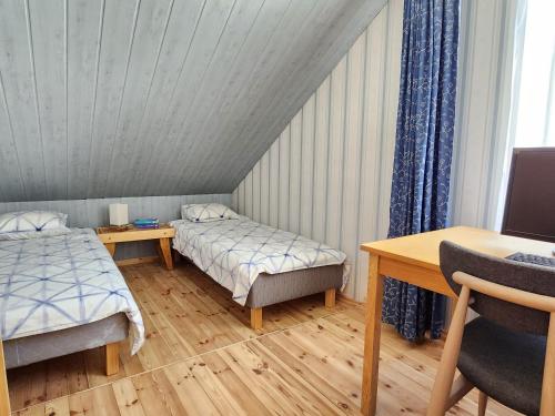 Cette chambre comprend deux lits, un bureau et une table. dans l'établissement Jannseni House, à Pärnu