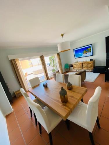 a dining room with a wooden table and white chairs at Cabedelo BEACH LOFT, quartos em apartamento compartilhado a 5 minutos da praia in Darque