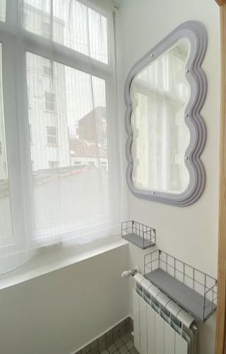 a bathroom with a mirror and a radiator and a window at Apartamento C/ Concepción Arenal in Ferrol