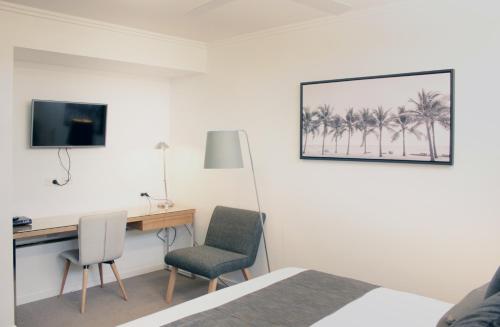 a hotel room with a desk and two chairs at Pacific Sands Apartments Mackay in Mackay