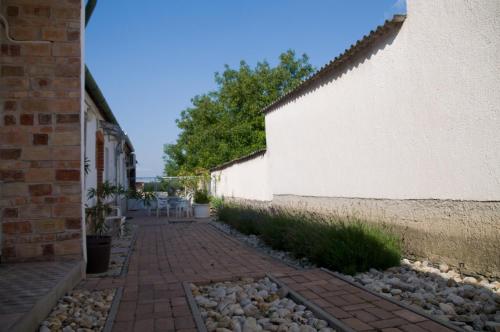 a brick walkway next to a white wall with plants at Nótás Tücsök Vendégház in Agyagosszergény
