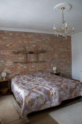 a large bed in a room with a brick wall at Nótás Tücsök Vendégház in Agyagosszergény