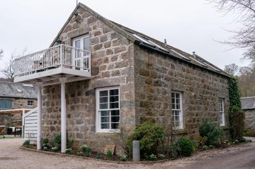 a stone house with a balcony on the side of it at Ranch House Cottage Inverurie 