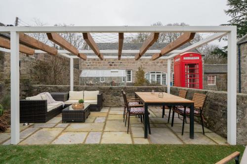 a patio with a table and a red phone booth at Ranch House Cottage, Pet Friendly Stay, Inverurie in Thainstone