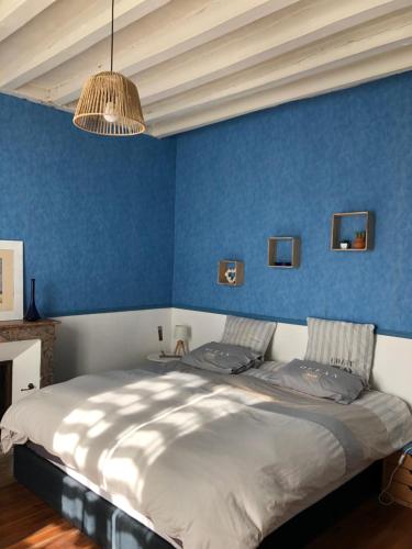une chambre avec des murs bleus et un grand lit dans l'établissement Maison de famille, à Saint-Mars-dʼOutillé