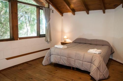 1 dormitorio con 1 cama en una habitación con ventanas en La Aljaba en San Carlos de Bariloche