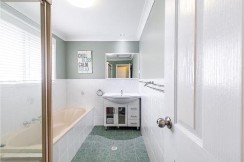 a white bathroom with a tub and a sink at Starfish at Anna Bay 4 Fishermans Bay Road in Anna Bay