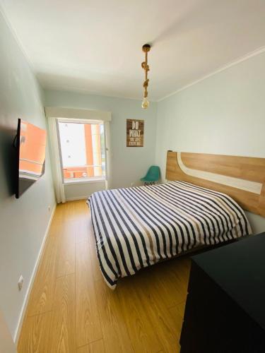 a bedroom with a bed with a striped blanket at Cabedelo BEACH LOFT, quartos em apartamento compartilhado a 5 minutos da praia in Darque