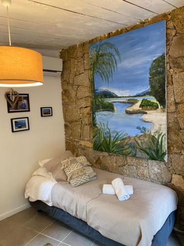 a bed in a room with a painting on the wall at Maranatha, front de mer avec plage in Porto-Vecchio