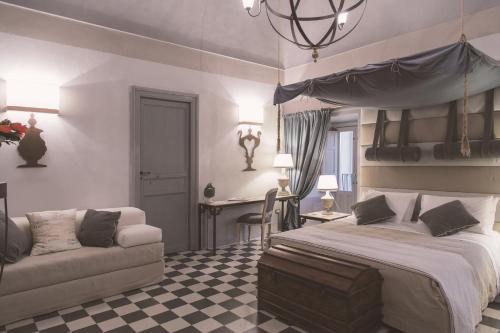 1 dormitorio con 1 cama y 1 sofá en Palazzo Trigona Suites, en Noto