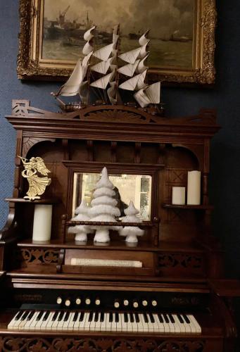 a piano with a christmas tree on top of it at Coppersmith Inn Bed And Breakfast in Galveston