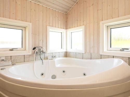 a bath tub in a bathroom with two windows at Holiday Home Sølvgranvej in Marielyst