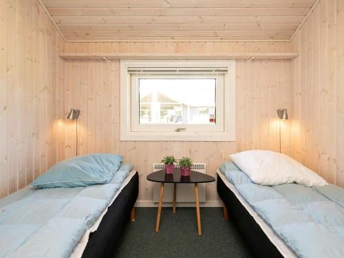 two beds in a room with a table and a window at Holiday Home Sølvgranvej in Marielyst