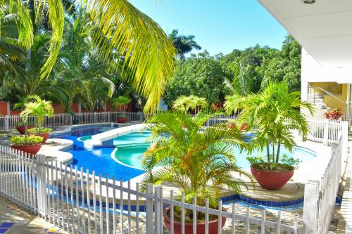 un complejo con piscina con palmeras y una valla blanca en Hotel Campestre Villa Ocha en Valledupar