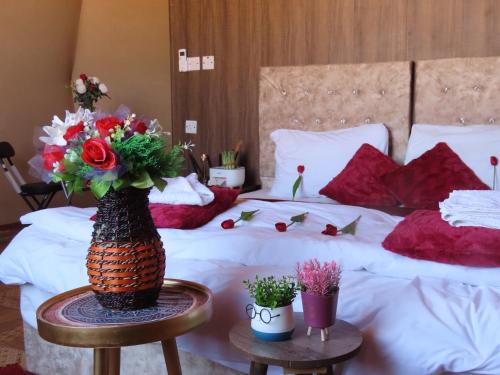 a bedroom with a bed with a vase of flowers on a table at Warm bubbles Wadi Rum in Wadi Rum