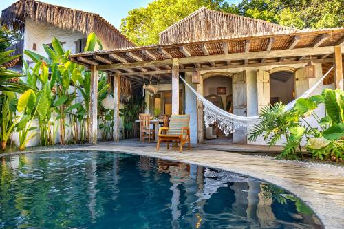 a house with a swimming pool in front of a house at Vila Rudá Trancoso in Trancoso