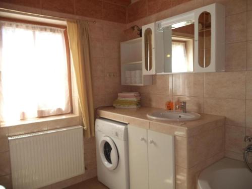 uma casa de banho com uma máquina de lavar roupa e um lavatório em RÉKA háziállatbarát nyaraló em Keszthely