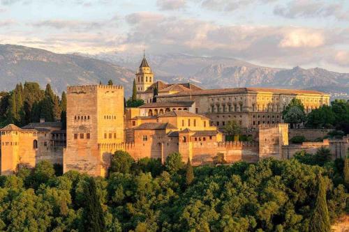 Granada, ciudad encantada في Cájar: قلعة كبيرة على تلة مع جبال في الخلفية