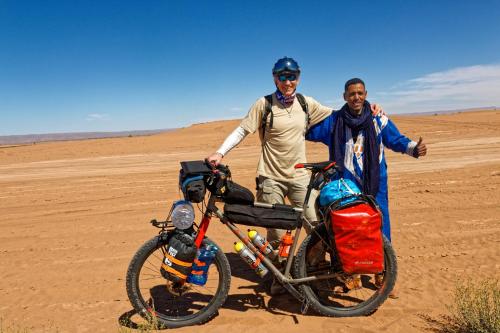 two men standing next to a motorcycle in the desert at Erg Chigaga Regency Camp in El Gouera