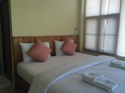a bedroom with two twin beds with pink pillows at Norn Nab Dao Rimkhong in Chiang Khan