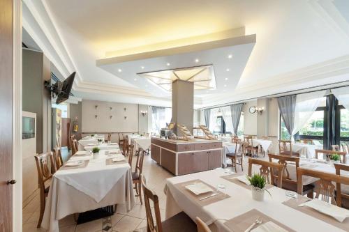 un restaurant avec des tables blanches, des chaises et des fenêtres dans l'établissement Best Western Hotel Imperiale, à Nova Siri Marina