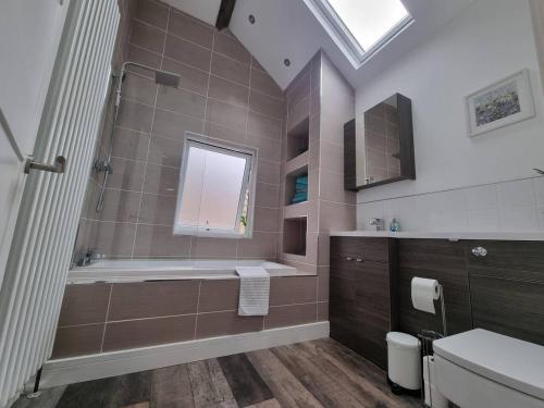 y baño con bañera y lavamanos. en Modern 4-Bedroom Townhouse With Private Garden en Abertillery