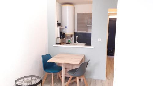 Il comprend une petite cuisine avec une table en bois et des chaises bleues. dans l'établissement Studio 302 au 15 rue Battant à Besançon, à Besançon