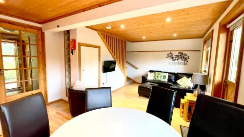 Spacious Primrose Lodge for 6 with Hot Tub at a Spa Resort في Chudleigh: غرفة معيشة مع أريكة وطاولة وكراسي