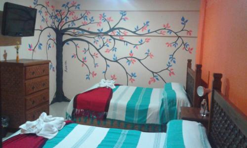 a bedroom with two beds with a tree mural on the wall at Hotel Amayal in San Cristóbal de Las Casas