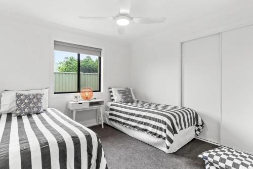 a bedroom with two beds and a desk and a window at 4-21 Maple Lane in Evans Head