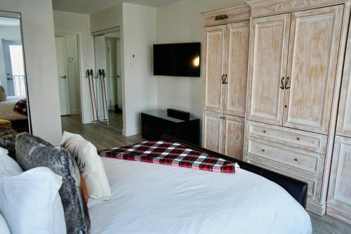 a bedroom with a bed and a large wooden cabinet at Le Rétro Chic à Mont-Tremblant in Mont-Tremblant