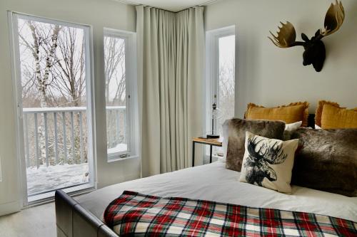 a bedroom with a bed and two windows at Le Rétro Chic à Mont-Tremblant in Mont-Tremblant