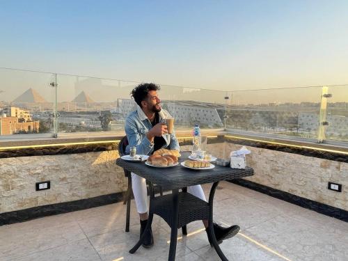 een man zit aan een tafel met eten op bij Jewel Grand Museum & Pyramids View in Giza