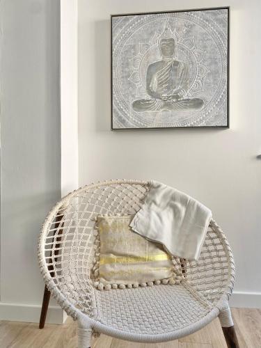 une chaise en rotin blanc avec un oreiller et une photo dans l'établissement LE PTIT VERT - Wifi - Confort - Entrée Autonome - Entre Gare et Centre, à Quimper